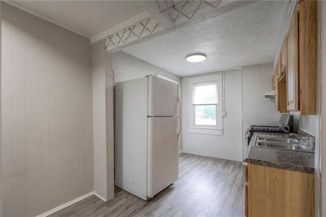336 N 16th St, Kansas City, KS 66102 - kitchen with freestanding refrigerator, light wood-type flooring, a textured ceiling, dark countertops, and stainless steel gas range oven