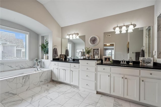 24631 W 126th St, Olathe, KS 66061 - bathroom with marble look tiles, vanity, vaulted ceiling, a garden tub, and plenty of natural light