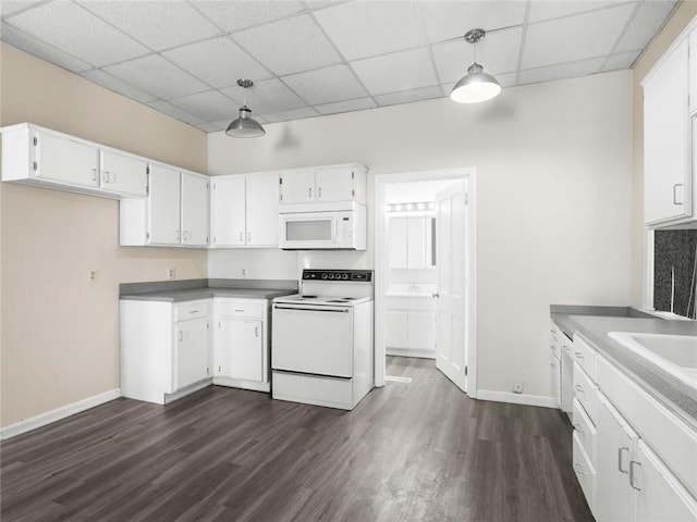 2703 Olive St, Saint Joseph, MO 64507 - kitchen featuring white appliances, a drop ceiling, dark wood-style flooring, white cabinetry, and pendant lighting