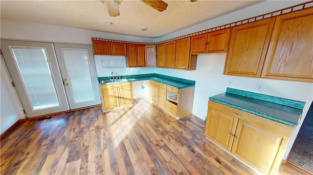 526 S W St, Nevada, MO 64772 - kitchen featuring brown cabinetry, a textured ceiling, wood finished floors, and a ceiling fan