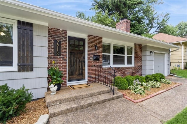 7718 Pawnee St, Prairie Village, KS 66208 - view of exterior entry with a chimney, an attached garage, brick siding, and covered porch