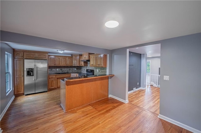 3620 Smart Ave, Kansas City, MO 64124 - kitchen featuring stainless steel fridge, black / electric stove, a peninsula, brown cabinets, and backsplash