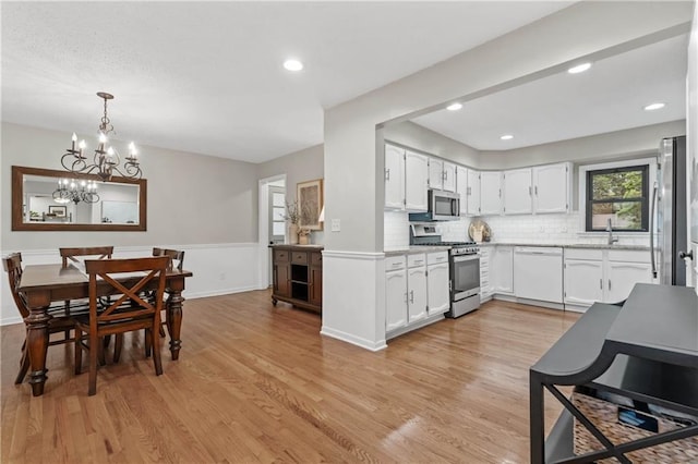 8039 Kessler St, Overland Park, KS 66204 - kitchen featuring stainless steel appliances, light wood-type flooring, light countertops, a chandelier, and white cabinets