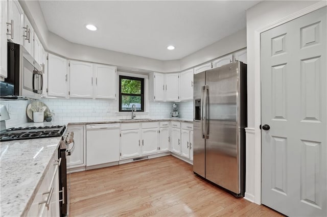 8039 Kessler St, Overland Park, KS 66204 - kitchen featuring stainless steel appliances, light wood-type flooring, white cabinetry, tasteful backsplash, and recessed lighting