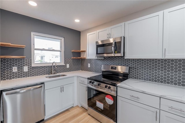 911 SE Hampton Ct, Lees Summit, MO 64063 - kitchen with stainless steel appliances, open shelves, light countertops, light wood-style floors, and decorative backsplash