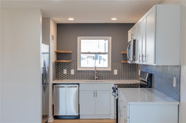 911 SE Hampton Ct, Lees Summit, MO 64063 - kitchen with stainless steel appliances, light countertops, open shelves, white cabinetry, and backsplash