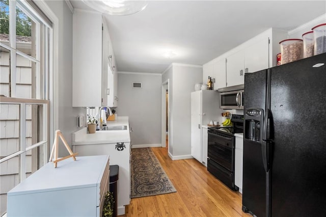8315 Sagamore Rd, Leawood, KS 66206 - kitchen featuring black appliances, light wood-style floors, light countertops, crown molding, and white cabinets
