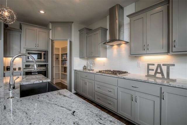 18421 Caenen St, Overland Park, KS 66013 - kitchen featuring wall chimney range hood, gray cabinets, stainless steel appliances, tasteful backsplash, and light stone counters