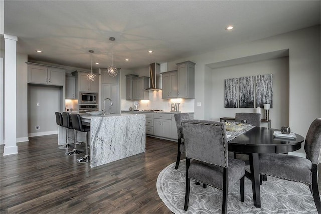 18421 Caenen St, Overland Park, KS 66013 - kitchen with gray cabinetry, stainless steel appliances, wall chimney exhaust hood, tasteful backsplash, and a center island with sink