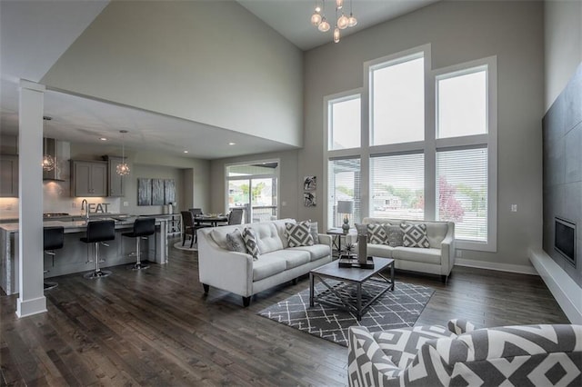 18421 Caenen St, Overland Park, KS 66013 - living area featuring a chandelier, dark wood-style flooring, a high ceiling, and a glass covered fireplace