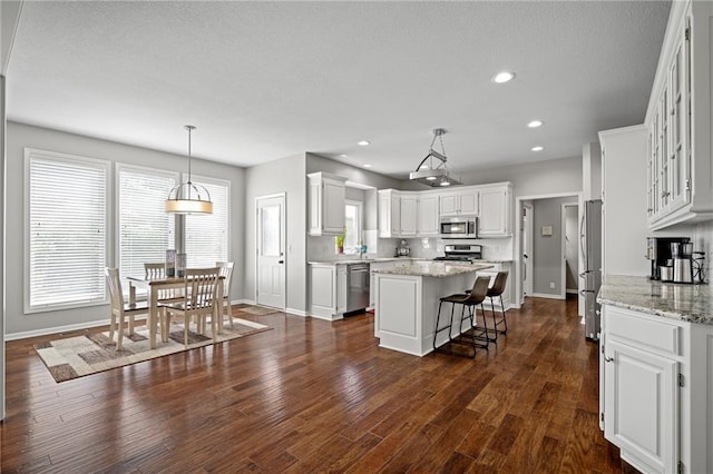 21502 W 98th Ter, Lenexa, KS 66220 - kitchen featuring stainless steel appliances, a center island, white cabinets, a kitchen bar, and a textured ceiling