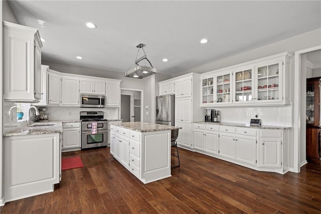 21502 W 98th Ter, Lenexa, KS 66220 - kitchen with appliances with stainless steel finishes, white cabinets, a center island, glass insert cabinets, and recessed lighting