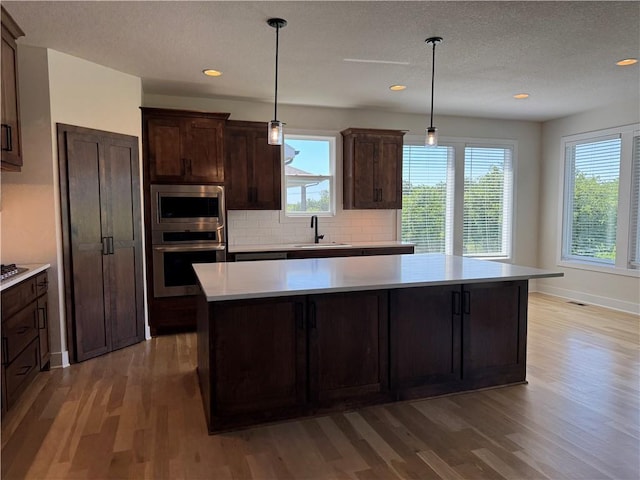 22415 87th Ter, Lenexa, KS 66227 - kitchen with appliances with stainless steel finishes, light wood-style flooring, light countertops, a kitchen island, and recessed lighting