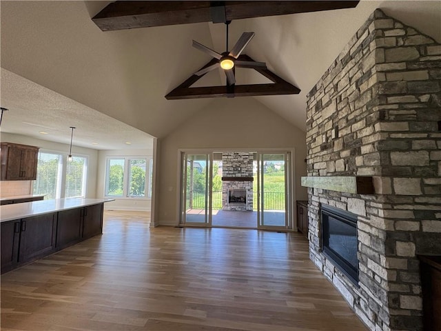 22415 87th Ter, Lenexa, KS 66227 - unfurnished living room with a stone fireplace, beam ceiling, high vaulted ceiling, ceiling fan, and wood finished floors