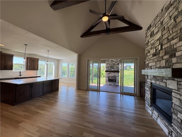 22415 87th Ter, Lenexa, KS 66227 - unfurnished living room featuring a fireplace, beam ceiling, plenty of natural light, wood finished floors, and high vaulted ceiling