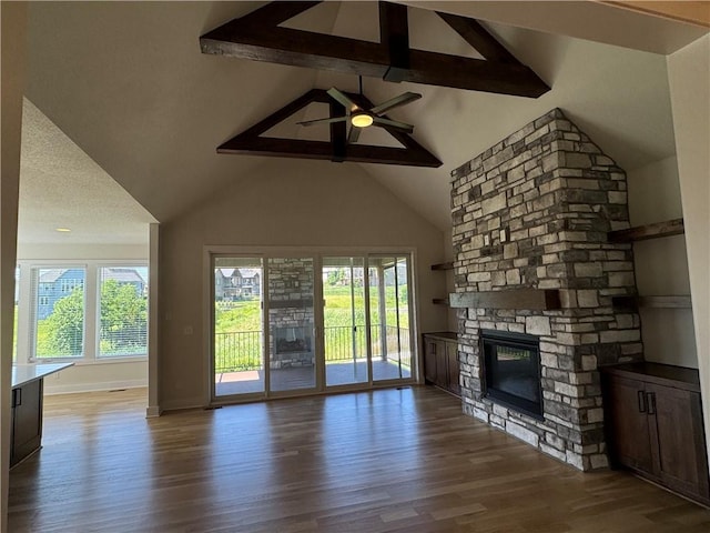 22415 87th Ter, Lenexa, KS 66227 - unfurnished living room featuring plenty of natural light, wood finished floors, a fireplace, beam ceiling, and ceiling fan
