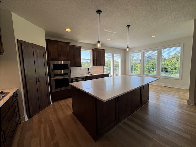 22415 87th Ter, Lenexa, KS 66227 - kitchen featuring stainless steel appliances, dark wood-style flooring, a center island, light countertops, and recessed lighting