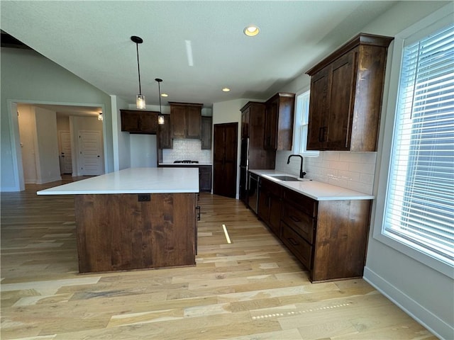 22415 87th Ter, Lenexa, KS 66227 - kitchen with light wood finished floors, a center island, tasteful backsplash, dark brown cabinets, and light countertops