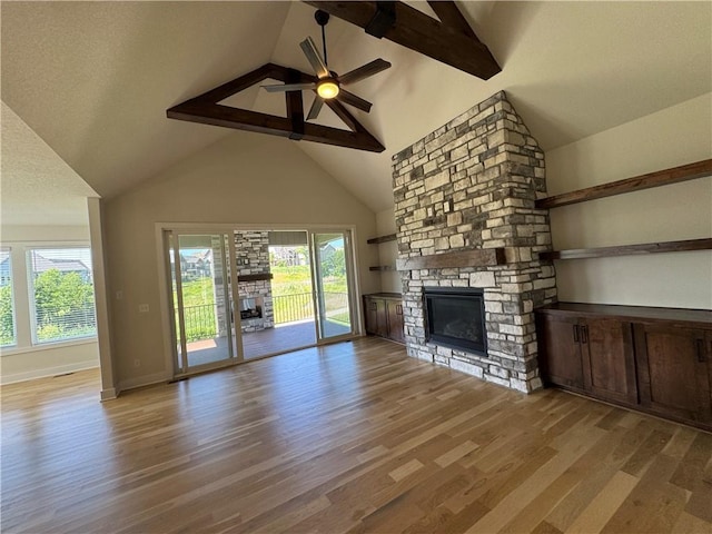 22415 87th Ter, Lenexa, KS 66227 - unfurnished living room with a stone fireplace, wood finished floors, healthy amount of natural light, high vaulted ceiling, and beamed ceiling