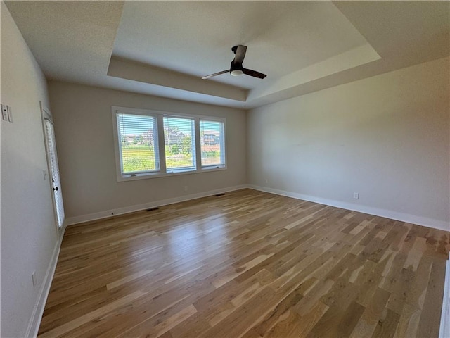 22415 87th Ter, Lenexa, KS 66227 - empty room featuring a raised ceiling, light wood-style floors, and a ceiling fan
