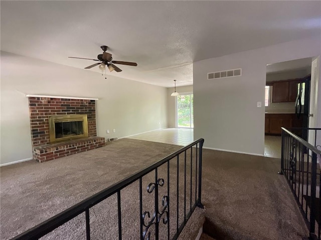 3212 Canterbury Rd, Blue Springs, MO 64015 - unfurnished living room with dark carpet, a ceiling fan, and a fireplace