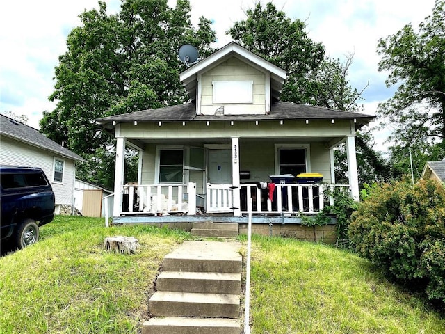 5433 E 29th St, Kansas City, MO 64128 - view of front facade with covered porch, a front lawn, and a shingled roof