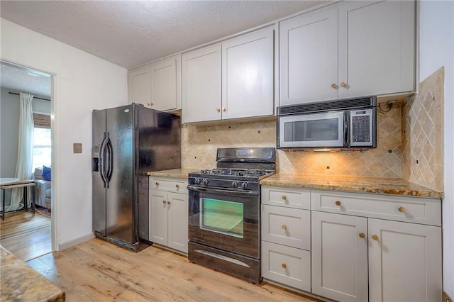 7000 Dearborn St, Overland Park, KS 66204 - kitchen with black appliances, light wood-type flooring, light stone counters, tasteful backsplash, and a textured ceiling
