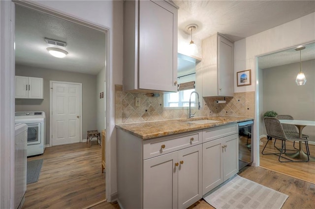 7000 Dearborn St, Overland Park, KS 66204 - kitchen featuring washer / dryer, light wood-style flooring, decorative backsplash, light stone counters, and pendant lighting