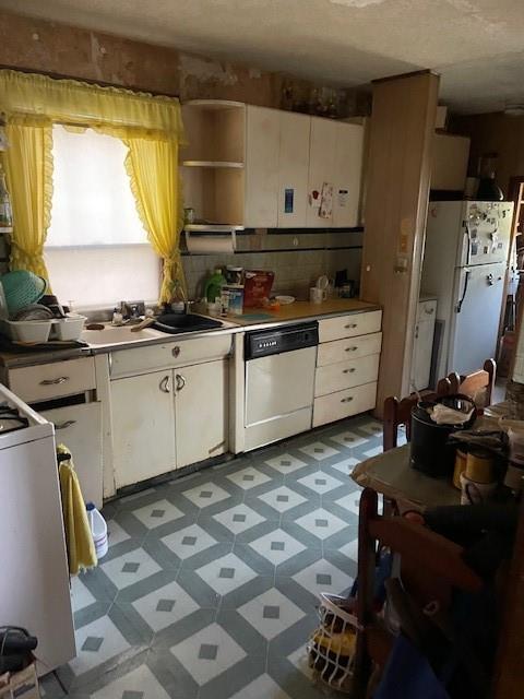 653 Elmwood Ave, Kansas City, MO 64124 - kitchen with dishwasher, freestanding refrigerator, white cabinetry, and light floors