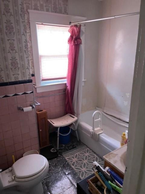 653 Elmwood Ave, Kansas City, MO 64124 - full bath with wallpapered walls, shower / tub combo with curtain, tile walls, and wainscoting