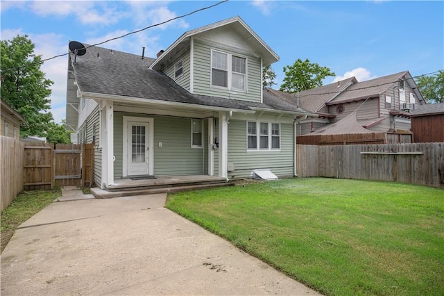704 Lincoln St, Coffeyville, KS 67337 - back of property featuring a fenced backyard, a shingled roof, covered porch, and a gate