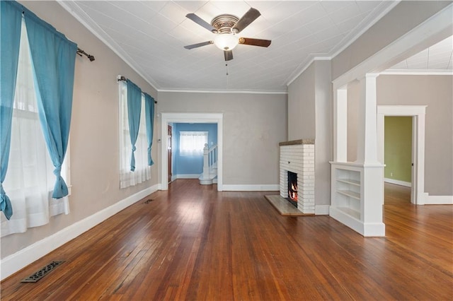 704 Lincoln St, Coffeyville, KS 67337 - unfurnished living room featuring ceiling fan, a brick fireplace, wood-type flooring, and crown molding