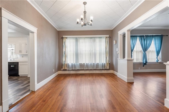 704 Lincoln St, Coffeyville, KS 67337 - unfurnished dining area with ornamental molding, wood-type flooring, a chandelier, and decorative columns
