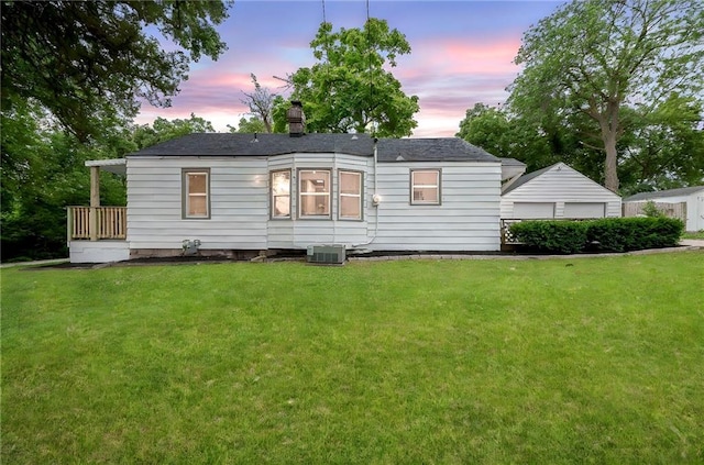 9521 W 60th St, Merriam, KS 66203 - back of house at dusk featuring a lawn, a chimney, a detached garage, and an outbuilding