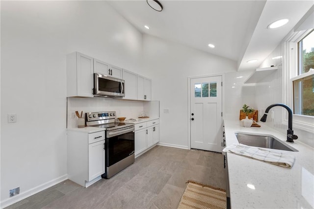 9521 W 60th St, Merriam, KS 66203 - kitchen featuring appliances with stainless steel finishes, decorative backsplash, white cabinets, lofted ceiling, and recessed lighting