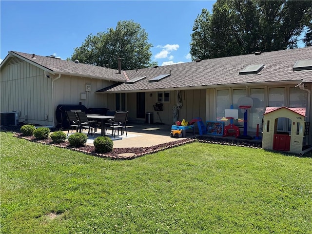 906 S Denman, Chanute, KS 66720 - back of property featuring board and batten siding, a lawn, a patio area, and a shingled roof