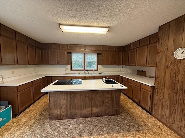 529 S Business Highway 13, Lexington, MO 64067 - kitchen featuring light countertops, a center island, black electric cooktop, a textured ceiling, and light floors