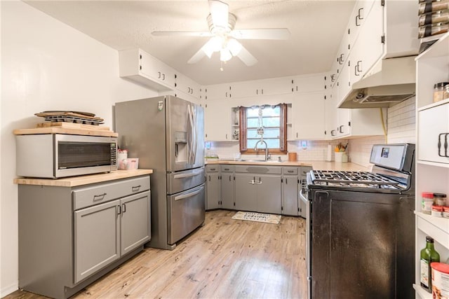 702 Green St, Lees Summit, MO 64063 - kitchen with gray cabinetry, appliances with stainless steel finishes, under cabinet range hood, a ceiling fan, and light wood-style flooring