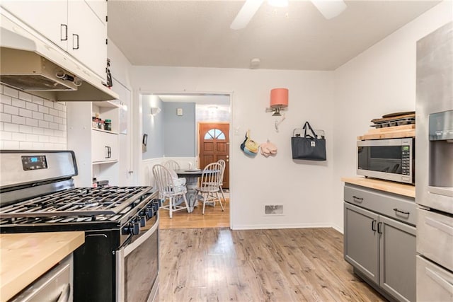 702 Green St, Lees Summit, MO 64063 - kitchen featuring appliances with stainless steel finishes, under cabinet range hood, gray cabinetry, ceiling fan, and light wood-style flooring