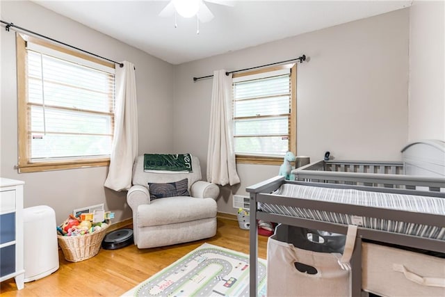 702 Green St, Lees Summit, MO 64063 - bedroom featuring a crib, wood finished floors, and a ceiling fan