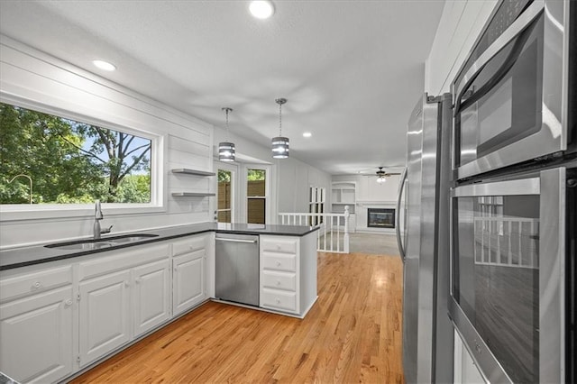 1467 E Orleans Dr, Olathe, KS 66062 - kitchen featuring stainless steel appliances, dark countertops, a peninsula, white cabinetry, and light wood-style floors