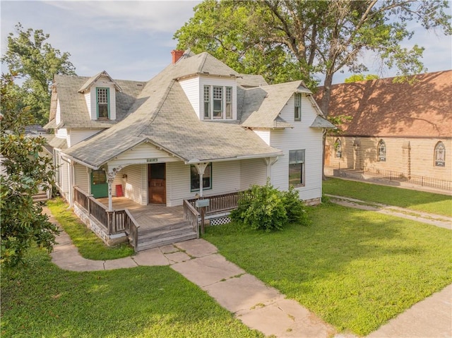 708 Osage St, Neodesha, KS 66757 - view of front facade featuring a porch, a front yard, a chimney, and a shingled roof