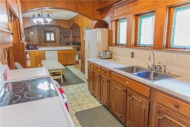 708 Osage St, Neodesha, KS 66757 - kitchen featuring white appliances, light floors, arched walkways, healthy amount of natural light, and wooden walls