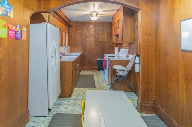 708 Osage St, Neodesha, KS 66757 - kitchen with white fridge with ice dispenser, arched walkways, light floors, range, and wood walls