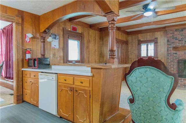 708 Osage St, Neodesha, KS 66757 - kitchen with white dishwasher, wood walls, light countertops, light carpet, and arched walkways