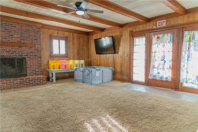 708 Osage St, Neodesha, KS 66757 - unfurnished living room featuring beam ceiling, ceiling fan, wood walls, a fireplace, and tile patterned flooring