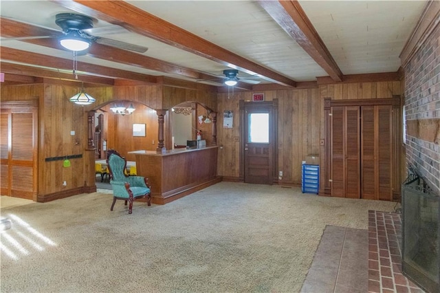 708 Osage St, Neodesha, KS 66757 - sitting room featuring a ceiling fan, beamed ceiling, a fireplace, wooden walls, and arched walkways