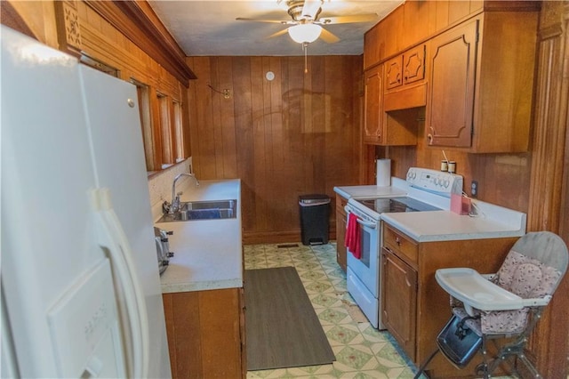 708 Osage St, Neodesha, KS 66757 - kitchen with white appliances, light floors, brown cabinets, wood walls, and ceiling fan