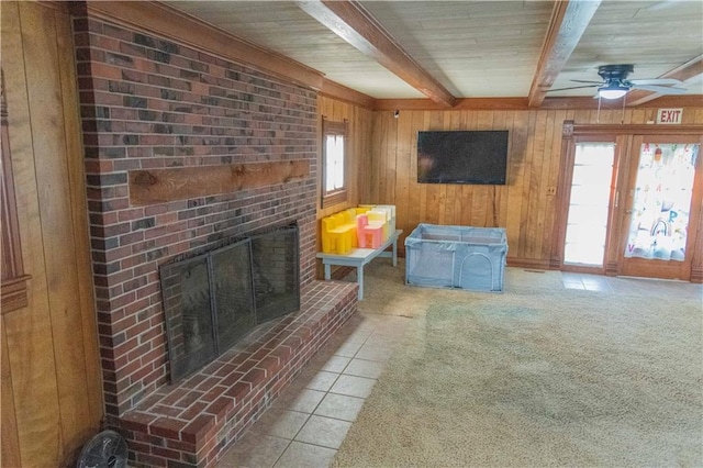 708 Osage St, Neodesha, KS 66757 - tiled living area featuring beam ceiling, wooden walls, a ceiling fan, and a brick fireplace