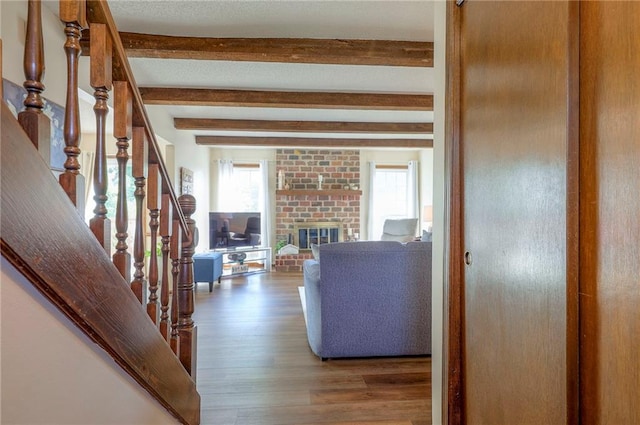 7103 Mastin St, Merriam, KS 66203 - living area featuring beamed ceiling, wood finished floors, healthy amount of natural light, stairway, and a fireplace